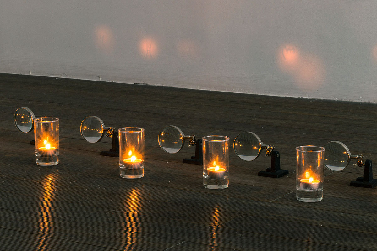“Fire Symbol”  2013. Engraving on glass cup, magnifier, candle. Photo by Wang Wenlong. Courtesy of Shanghai 21st Century Minsheng Art Museum.